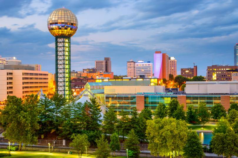 Skyline of Knoxville, Tennessee, featuring the Sunsphere, modern buildings, and trees under a cloudy sky. Skyline of Knoxville, Tennessee, featuring the Sunsphere, modern buildings, and trees under a cloudy sky.